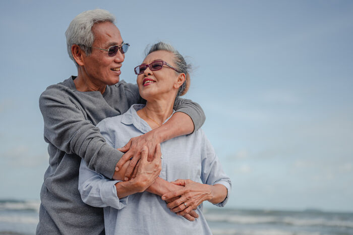 An older couple embracing on the beach, reflecting things doctors refuse to do for long-term health.
