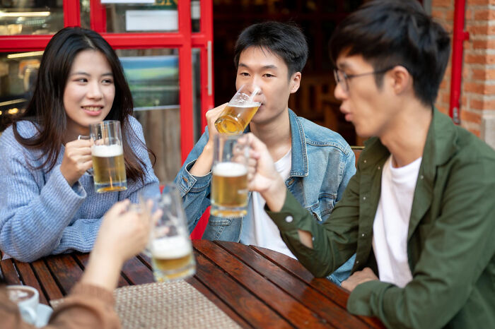 Three friends are drinking beer at an outdoor cafe, which could be one of the things doctors refuse to do.