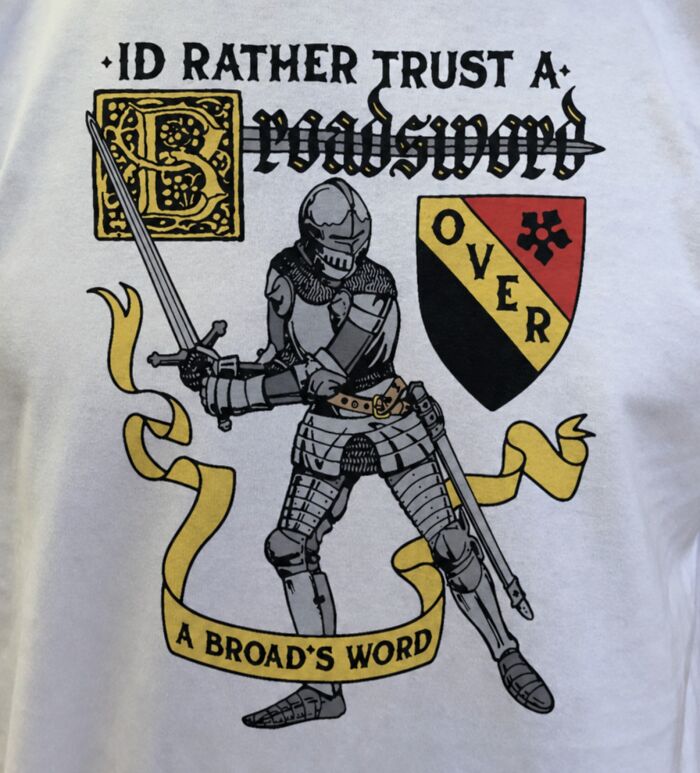 A white iconic shirt featuring a knight, broadsword, and the text: ID RATHER TRUST A BROADSWORD OVER A BROADS WORD.