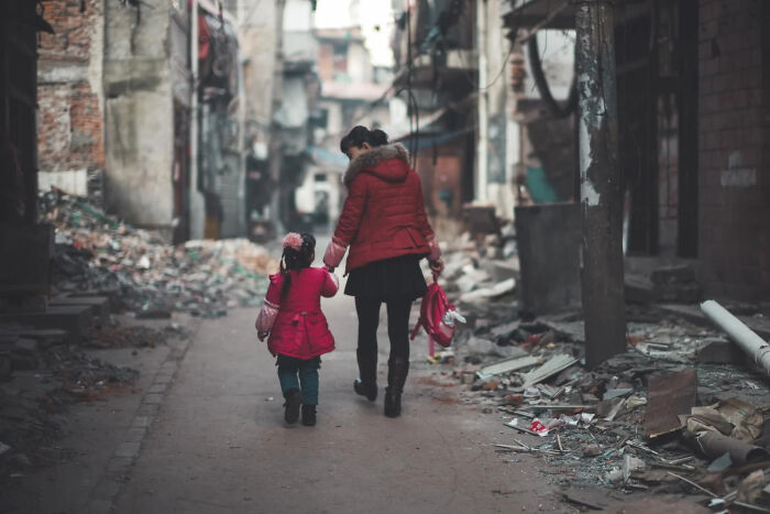 A woman sits amidst rubble, a poignant scene of the world, capturing a winning image for European Photography Awards.