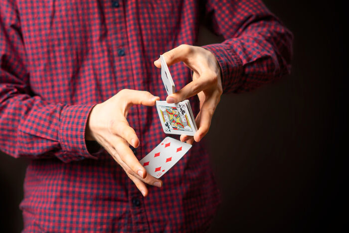 A person performing a card trick, demonstrating a new skill learned in 30 days.