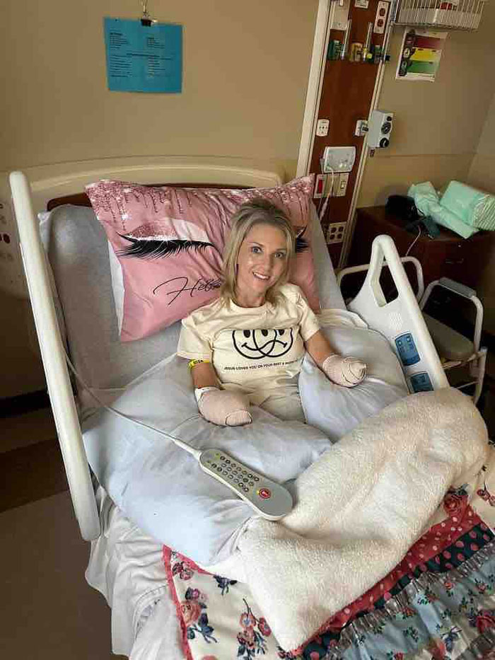 A woman who had both legs and hands amputated after surgery smiles from her hospital bed. A woman who had both legs and hands amputated after surgery smiles from her hospital bed.
