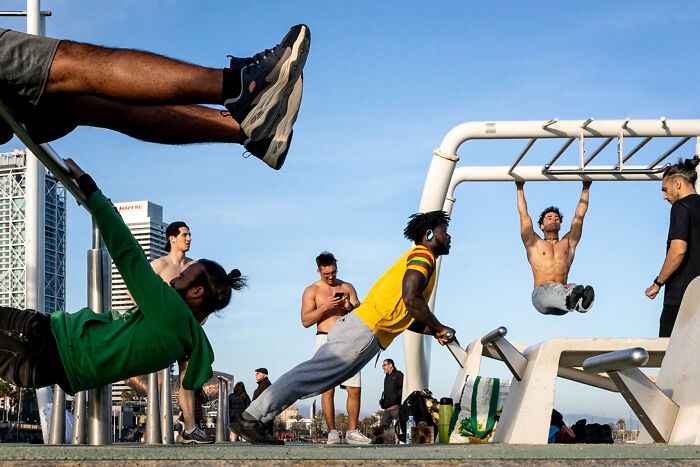 Men exercising at an outdoor gym, performing various calisthenics, highlighting the art of street photography.