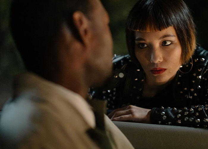 A woman with a blunt bob haircut and studded jacket intensely looking at a man, recalling worst first dates with women.