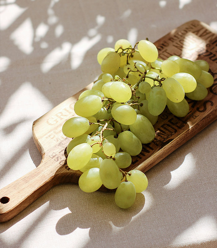 A bunch of green grapes on a wooden cutting board. A doctor shares five things parents should not allow children to do.