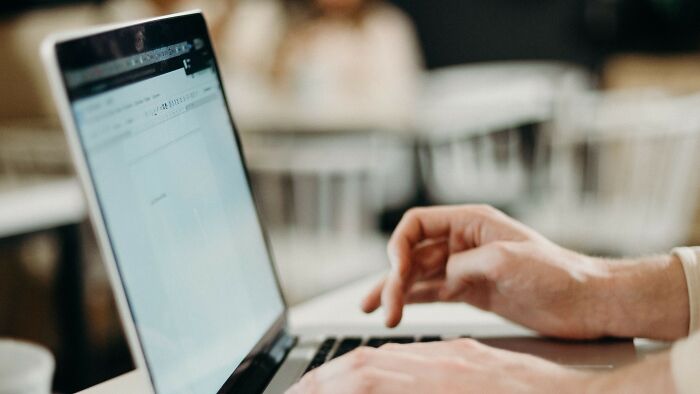 A person is typing on a laptop, potentially controlling boyfriend eats or daily habits.