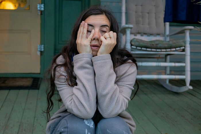 A woman looking distressed and covering her face, perhaps contemplating breakup-worthy things her partner did.