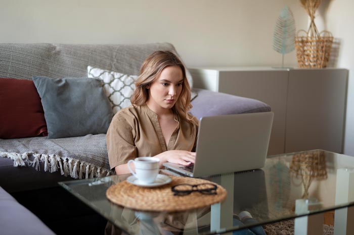 A woman works on her laptop at home, highlighting remote work scenarios and dumb work rules.