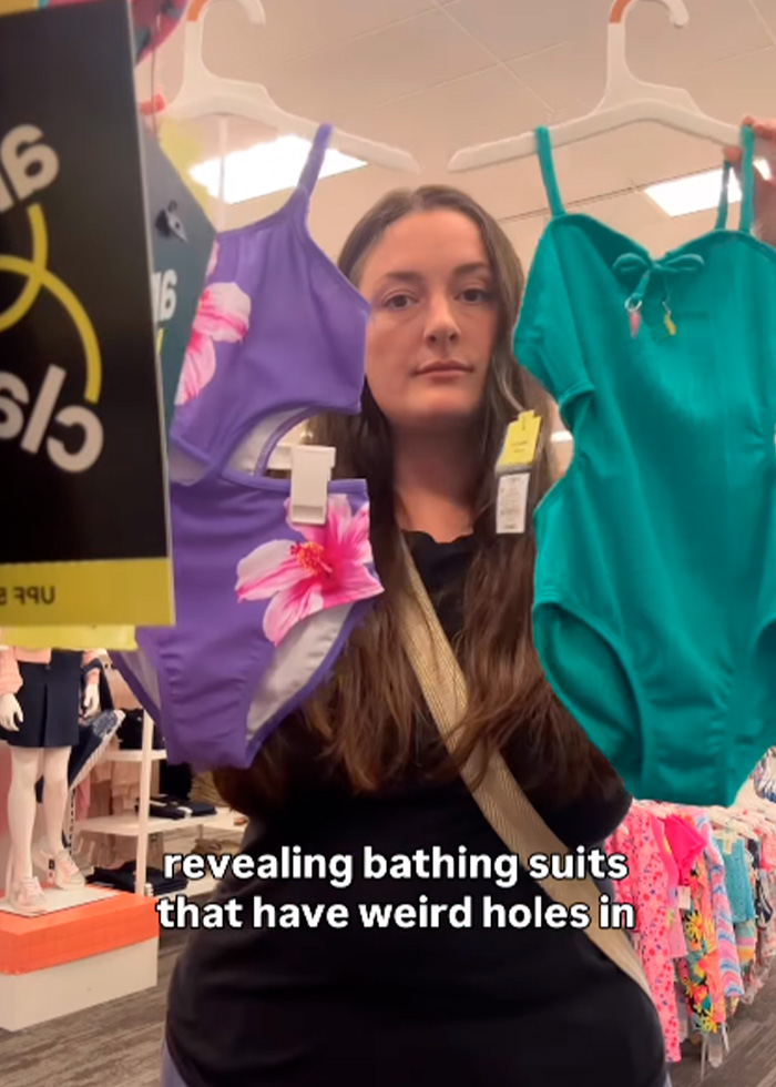 A shopper in a store holding up two pieces of kids clothing for back-to-school: a purple floral swimsuit and a teal swimsuit. A shopper in a store holding up two pieces of kids clothing for back-to-school: a purple floral swimsuit and a teal swimsuit.
