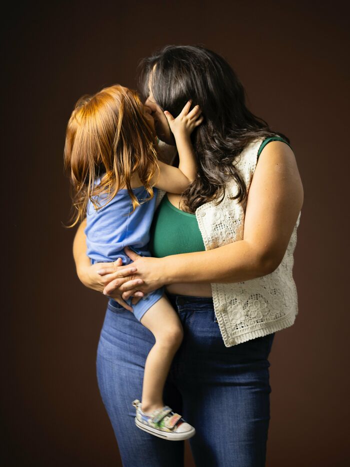 A woman holding and kissing a young natural redhead child, celebrating natural redheads.