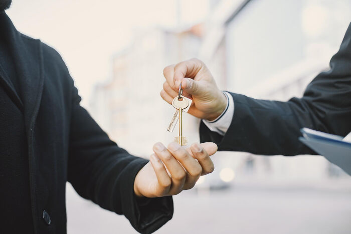 A pair of hands exchanging keys, suggesting a transition or consequence from shocking employee stories, possibly being fired.