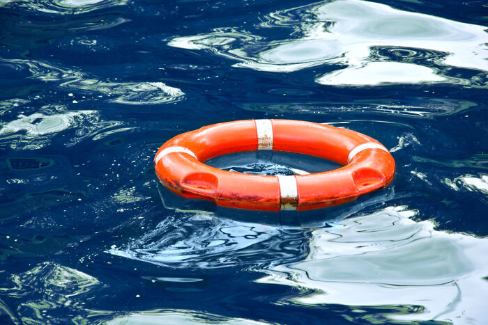 An orange life buoy floats in dark blue water, symbolizing stories from people who crossed the line between life and what comes after.
