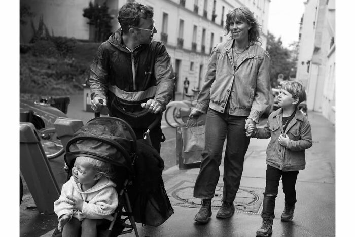 A family with two children, one in a stroller, walking on a Paris street captured in a perfectly timed photo by Gaspard Claude.