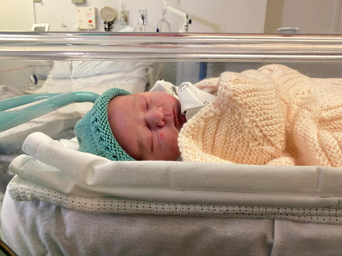 A newborn baby sleeping in a hospital bassinet, symbolizing new beginnings and family, which can be affected by dumb reasons couples divorce.