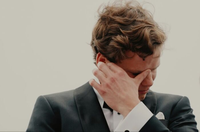 A man in a suit wiping his eye, showing an emotional wedding moment.