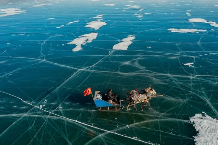 Murat Bakmaz captures the beauty of everyday life: A horse-drawn sleigh with a Turkish flag on a vast, cracked icy surface.