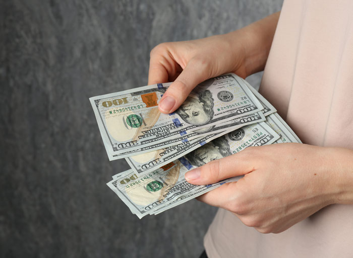 Woman counts money, symbolizing the financial dispute over a gift and missing necklace with her ex-MIL. Woman counts money, symbolizing the financial dispute over a gift and missing necklace with her ex-MIL.