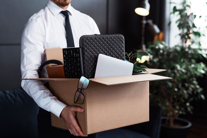 Man holds a box of personal belongings after being fired, showing the consequence for the workplace bully stealing credit. Man holds a box of personal belongings after being fired, showing the consequence for the workplace bully stealing credit.