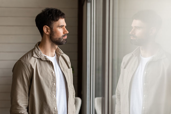A man looking reflectively at his reflection in a glass, contemplating the workplace bully situation. A man looking reflectively at his reflection in a glass, contemplating the workplace bully situation.