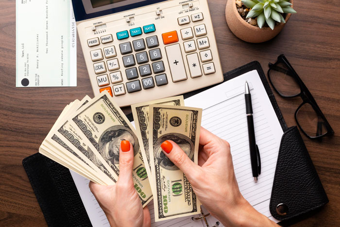 A woman counting cash, representing the financial loss from a destroyed home, trusted roommate, and cats. A woman counting cash, representing the financial loss from a destroyed home, trusted roommate, and cats.
