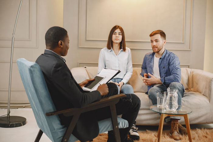 A poly wife and her husband discussing their relationship with a therapist, seeking guidance on a polyamorous dynamic. A poly wife and her husband discussing their relationship with a therapist, seeking guidance on a polyamorous dynamic.