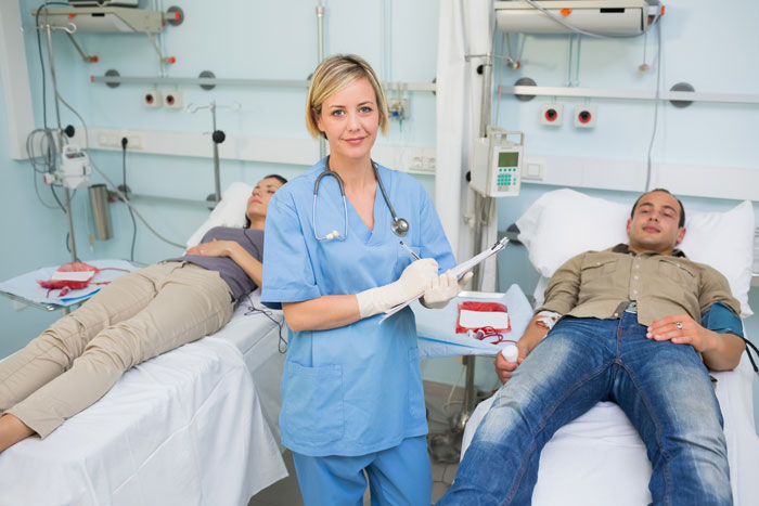 An ER nurse in scrubs stands between two patients, holding a clipboard, in a hospital room, highlighting the ER nurse's role. An ER nurse in scrubs stands between two patients, holding a clipboard, in a hospital room, highlighting the ER nurse's role.