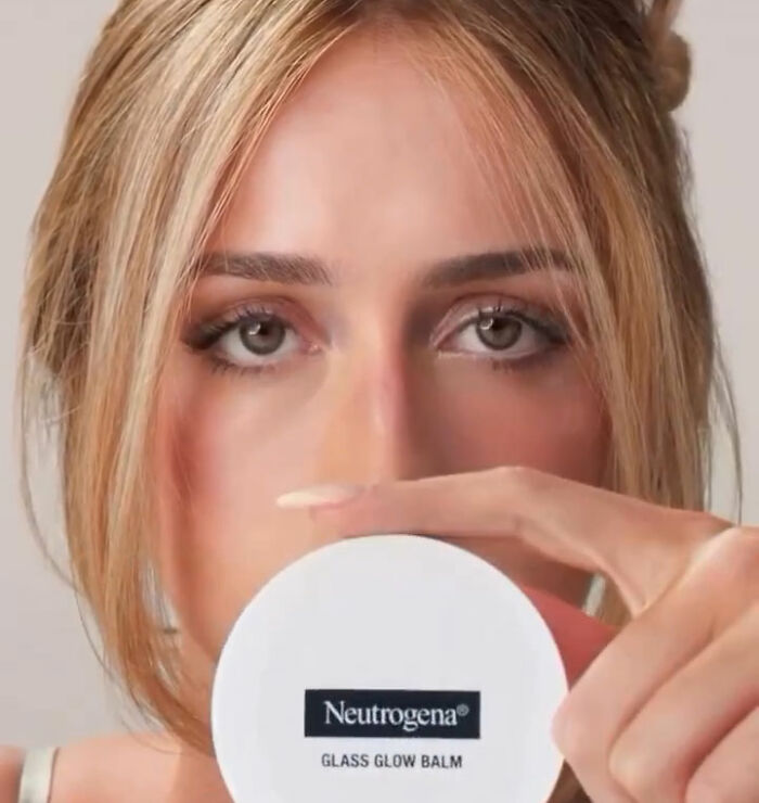 A close-up of a woman holding Neutrogena Glass Glow Balm, amidst news of Neutrogena's stock and Hayden Panettiere.