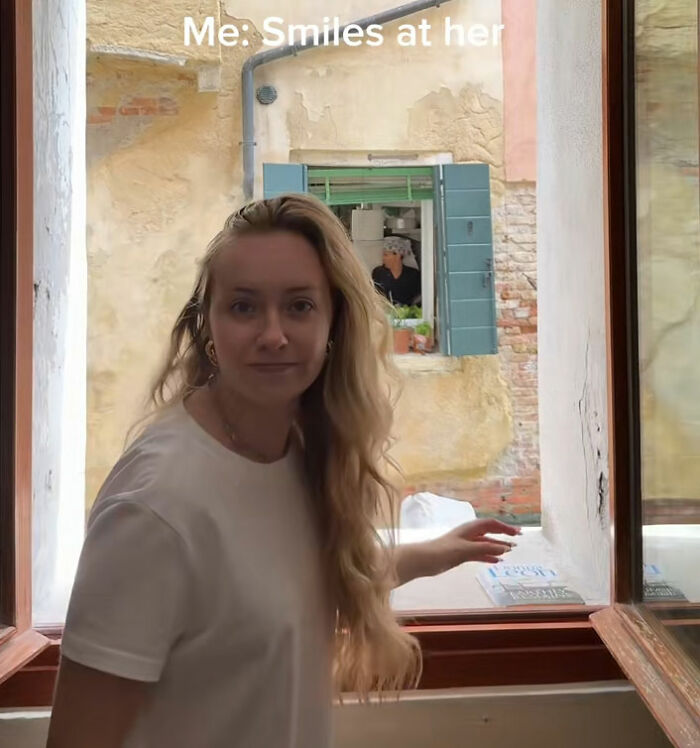 Influencer smiles at a Venetian woman who appears in her window. The influencer tries to call out Venetians. Influencer smiles at a Venetian woman who appears in her window. The influencer tries to call out Venetians.