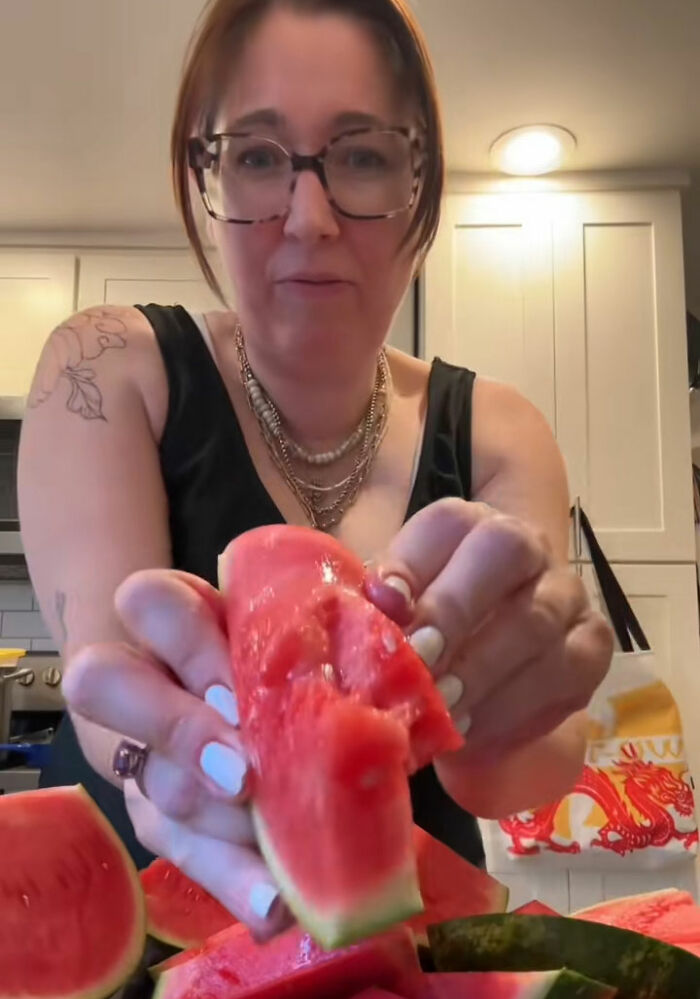 A woman with glasses holding a piece of watermelon, part of the viral TikTok trend exposing fake foods Americans eat everyday. A woman with glasses holding a piece of watermelon, part of the viral TikTok trend exposing fake foods Americans eat everyday.