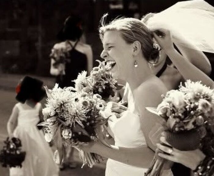 A candid shot of a bride laughing joyfully surrounded by bridesmaids, capturing funny wedding photos.
