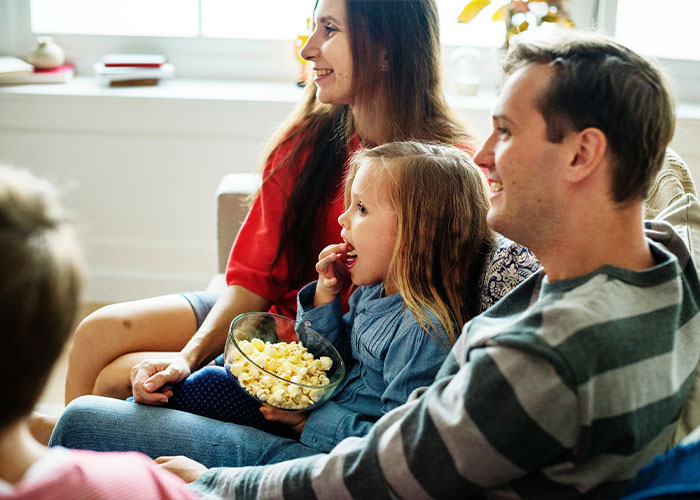 A family with children watches television together, highlighting things parents should never allow their children to do.