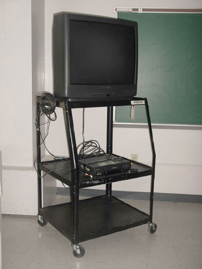 An old TV and VCR on a rolling cart in a classroom, a classic school memory for students of the past.