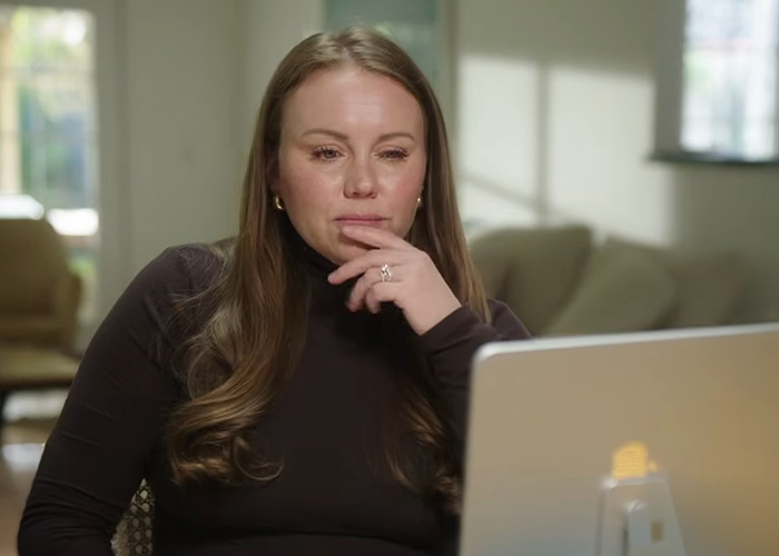 A woman who escaped a serial criminal sits in front of a laptop, deep in thought, reflecting on her captivity.