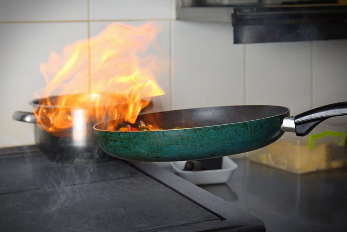 A cooking pan with flames, indicating a kitchen incident, potentially related to dumb work rules.