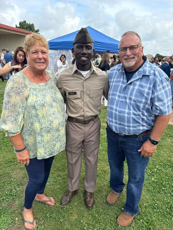 A couple stands proudly with their adopted son in uniform, celebrating their growing family after adopting kids. A couple stands proudly with their adopted son in uniform, celebrating their growing family after adopting kids.