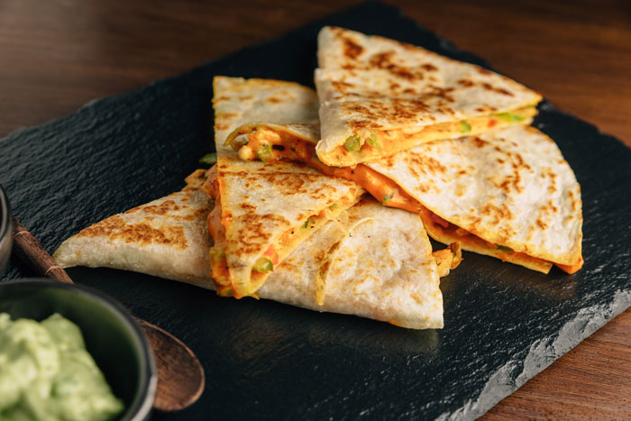 Several slices of quesadilla on a black serving board, symbolizing unhinged descriptions when names are forgotten.