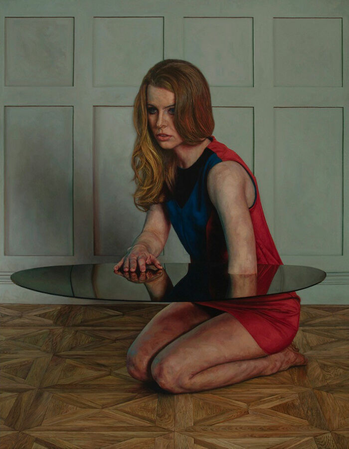 Hyperrealist paintings by Ian Cumberland: a woman in a red and blue dress kneels with a reflective surface at her waist.