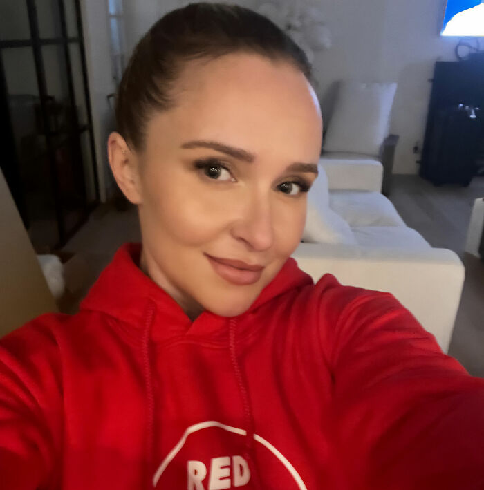 Hayden Panettiere in a red hoodie, smiling at the camera after a tragic passing.