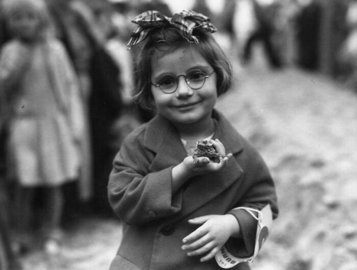 Vintage photo of a young girl with glasses holding a frog, demonstrating animals stealing the spotlight.