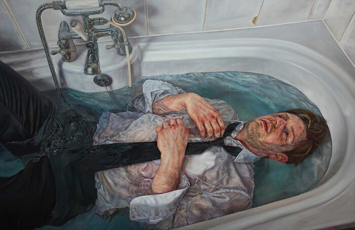 A hyperrealist painting by Ian Cumberland of a man in a suit lying in a bathtub full of water.