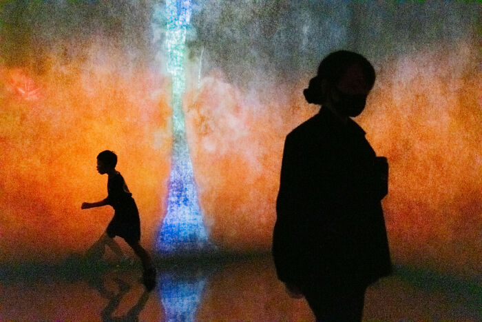 Silhouettes of people against a colorful, abstract light display, from the Edge Street Photography Awards.