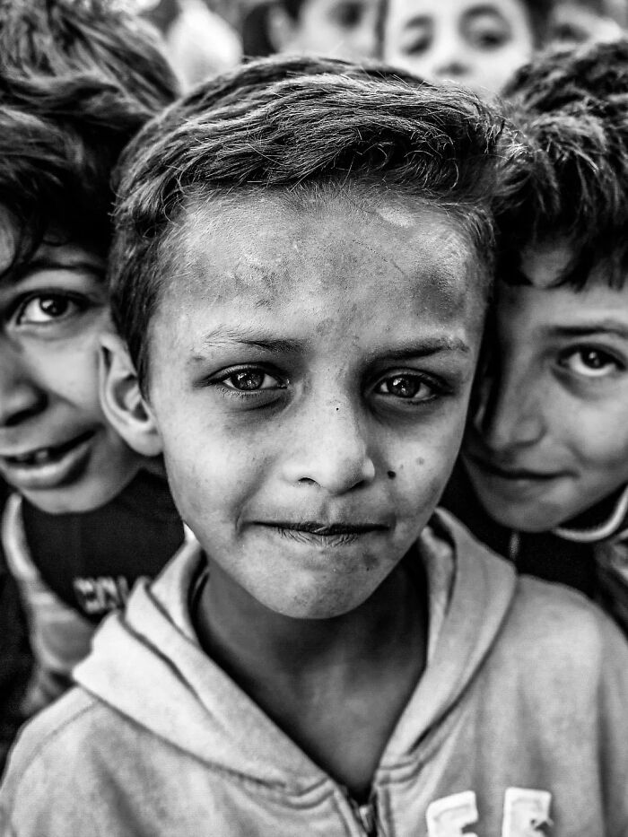A perfectly timed street photo by Mehmet Bayram features a serious boy surrounded by others, turning an everyday moment into art.