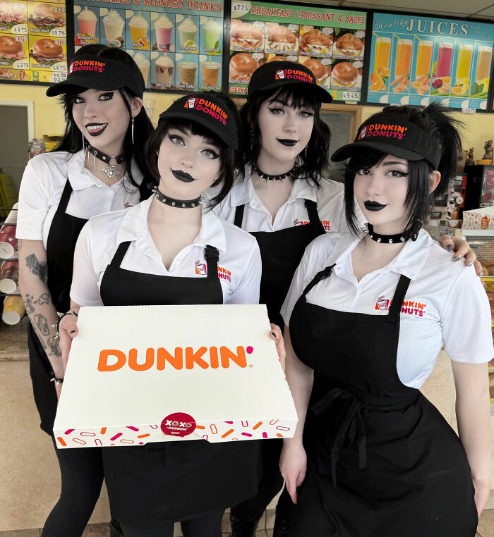 Four Goth baddie women in Dunkin Donuts uniforms, holding a Dunkin box, in a store. Four Goth baddie women in Dunkin Donuts uniforms, holding a Dunkin box, in a store.