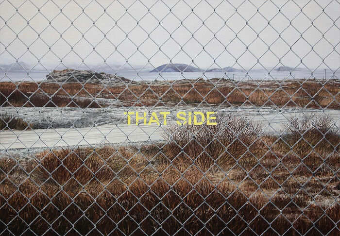 A hyperrealist painting by Ian Cumberland featuring a chain-link fence in front of a desolate landscape with the word THAT SIDE.