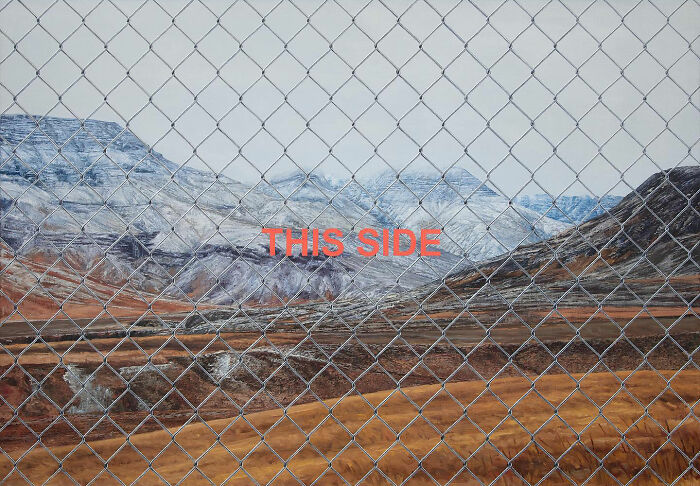 A hyperrealist painting by Ian Cumberland featuring a chain-link fence in front of snow-capped mountains with the word THIS SIDE.