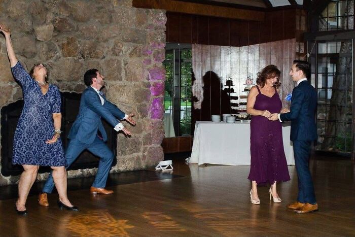 Iconic funny wedding photo showing guests dancing enthusiastically on a dance floor with stone fireplace backdrop.
