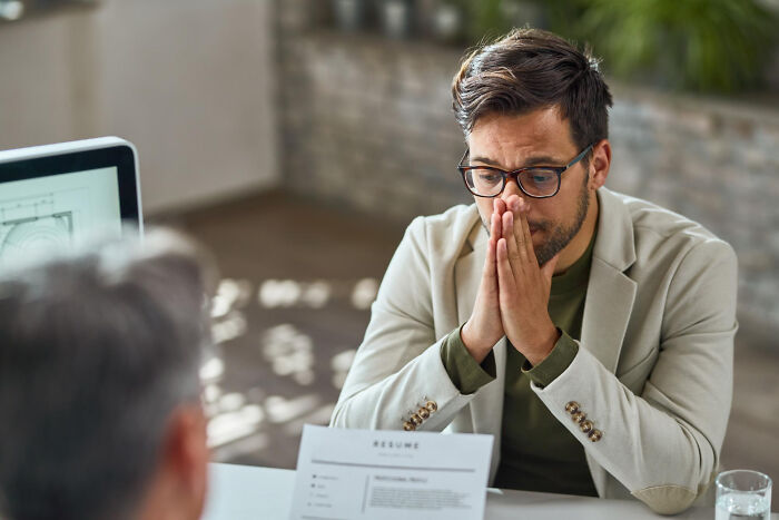 An anxious employee at a desk with a resume, perhaps facing a difficult conversation about being fired.