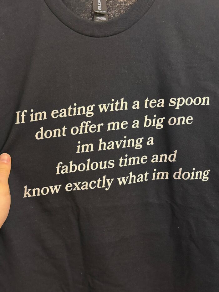 A black shirt with white text, featuring an iconic shirt design about eating with a teaspoon and knowing what I'm doing.