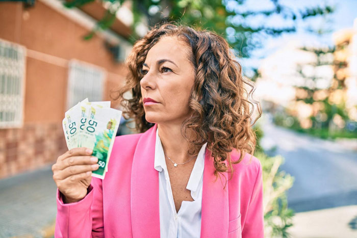 A thoughtful mom earns more holding money, contemplating funding kids and stepdaughter's children in a blended family. A thoughtful mom earns more holding money, contemplating funding kids and stepdaughter's children in a blended family.