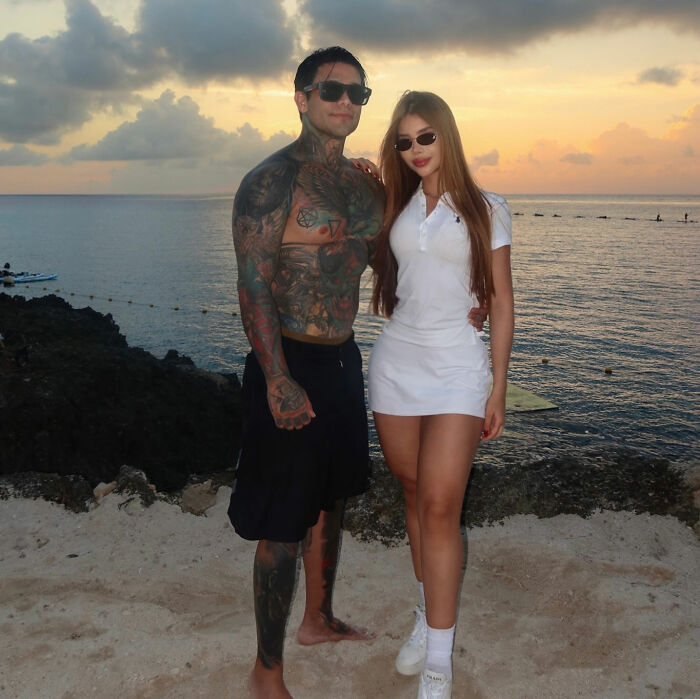An influencer and a woman posing at sunset on a beach after his mid-flight prank.